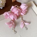 Primo piano di orecchini a fiore in tessuto rosa con perle e petali rugiadosi - Rosa
