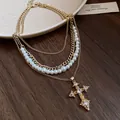 Close-up of vintage multi-layer necklace with pearls and rhinestone cross pendant - Necklace - Gold
