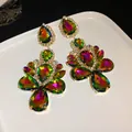 Detailed view of iridescent teardrop rhinestone dangle earrings on a white plate - Purple-Green