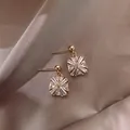 Exquisite close-up of geometric zircon stud earrings resting on elegant champagne silk fabric - Geometric Flower Style (HE1929) / Gold