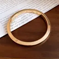 Vista dettagliata di un braccialetto rigido in resina dorata lucida minimalista - Oro