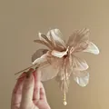 Detailed shot of an elegant handmade floral hair fork with pearls and dangling tassels - Hair Stick / Brown