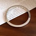 Dettaglio ravvicinato di un bracciale a cerchio lucido in argento dal design moderno. - Argento