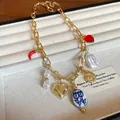 Detailed view of a vintage-style gold chain necklace featuring heart and chili charms. - Gold