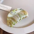 Close-up detail of a minimalist marble green acrylic hair claw clip on a white ceramic plate - Oval Hair Claw / Green