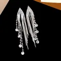 Close-up of elegant 18k gold plated silver needle long tassel earrings with disc charms - Silver