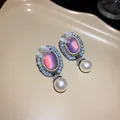 Close-up of vintage court style oval earrings with purple stone and hanging pearl - Silver Earring Post Style / Purple