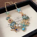 Nahaufnahme einer Meereshalskette mit Seesternen, Muscheln und Perlen in Box - Halskette / Gold-Blau