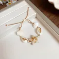 Handmade woven bracelet featuring ceramic starfish and natural shells for a beach look. - White Starfish Style