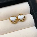 Close-up of gold circular stud earrings with elegant white heart inlay detail - Heart Style / Gold