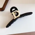 Detail of elegant black hair claw clip featuring a prominent gold-toned D emblem design - Metal Letter D Claw / Black