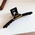 Close-up detail of matte black hair claw clip with gold triangle POWER ornament. - 20# Gripper - Black Triangle Letter