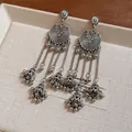 Detail of vintage silver bohemian earrings featuring round plates and bell tassels. - Silver