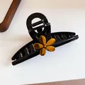 Detail view of a black shark hair claw clip decorated with a golden metallic flower - 22# Claw Clip - Black Flower