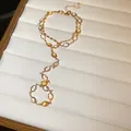 Close-up of vintage resin oval tassel necklace with gold chain on white display tray - Hand Chain / Gold/Multicolor