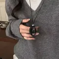 Close-up of a minimalist black resin hollow oval pendant necklace on a grey sweater - Black