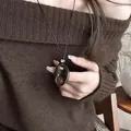 Detailed shot of a vintage resin hollow oval pendant necklace on a brown sweater - Brown