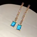 Gros plan d'élégantes longues boucles d'oreilles dorées avec pierres bleues rectangulaires - 56# Tige en Argent Sterling 925 - Gland Bleu Saphir / Or-Bleu