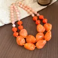 Detailansicht einer orangefarbenen Acryl-Perlenkette auf Holz- und Leinenuntergrund - Orange