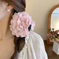 Detail view of a large pink lace flower hair claw clip worn on a braided hairstyle. - Lace Pink Flower Hair Claw