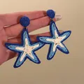 Close-up detail of blue and white woven star-shaped earrings for summer beach holiday. - Star-shaped Braided Style (17#) / Blue