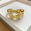 Detailed macro view of a gold-colored glossy intertwined knot cuff bracelet in a tray - Horsehoof Buckle Geometric Style (7)