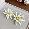 Close-up view of elegant white 3D flower earrings featuring vibrant yellow beaded centers - Earrings / White