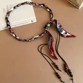Detail view of woven silk scarf belt with ethnic patterns and wooden beads - Green