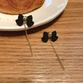Dettaglio di eleganti orecchini a fiocco nero con lunghe catene a nappa dorate - Stile Fiocco Nero con Nappina