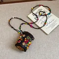 Detail of Bohemian coconut shell necklace with colorful beads on an artistic book background. - Multicolor Round Style / Brown
