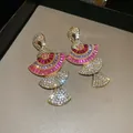 Close-up of gold fan-shaped earrings with pink and clear crystals - Geometric Tassel Shape