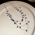 Primer plano de collar multicapa plateado con elegantes circonitas azules en forma de pera. - Gota de Agua Azul (Collar) / Plateado
