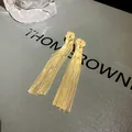 Detail shot of elegant long gold metal tassel knot drop earrings for stylish women. - Knotted Tassel Style / Gold