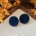 Macro detail of vintage dark blue velvet circular stud earrings on linen background - Blue