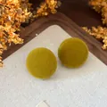Macro close-up of olive green velvet round stud earrings featuring a retro autumn fabric texture - Green