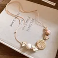Bohemian woven rattan and wooden bead necklace displayed on an artistic book detail view. - Necklace-White
