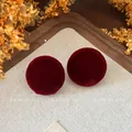 Detailed macro view of vintage burgundy velvet round stud earrings with autumn style - Red