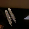 Close-up of shimmering long tassel earrings with multi-colored rhinestone accents - Multicolor Rhinestone Tassel Style / Gold