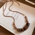 Close-up of bohemian wooden bead necklace with vintage floral and round disc elements - Necklace--Coffee