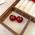 Detail of deep red cherry earrings with gold glitter inside a wooden box - Cherry (18#)
