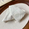 Gros plan d'une pince à cheveux en tissu crème avec un motif délicat de pois bleus - Blanc
