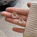 Vue détaillée de boucles d'oreilles couronne dorées avec perles et zircons fins - Or