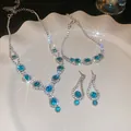 Vue détaillée d'une parure de bijoux en cristal bleu avec des strass étincelants sur une assiette - Ensemble de Trois Pièces Bracelet Collier Boucles d'oreilles Rondes Bleues (30#)