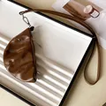 Detail shot of a brown faux leather croissant pouch necklace with a vintage texture - Brown