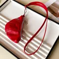 Close-up view of a chic red croissant-shaped faux leather coin purse necklace strap. - Red