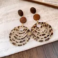 Close-up of retro Maillard style leopard print earrings featuring textured wooden disc accents. - Brown Round Pattern