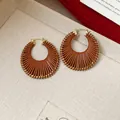 Macro view showing detail of brown woven leather hoop earrings with gold-toned metal hooks - Gold Hoop Earrings / Small / Brown