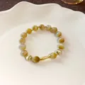 Primo piano di un elegante bracciale di perle con ciondolo a pesce dorato e pietre occhio di gatto. - Stile Ciondolo Pesciolino Occhio di Gatto (Bracciale 72#) / Con Confezione Regalo Squisita / Oro-Giallo