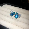 Primer plano de elegantes pendientes con cristales azules y perlas blancas en un joyero de lujo - Estilo Cuadrado Irregular Perla Artificial Strass / Azul