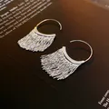 Detailed macro shot of elegant silver tassel earrings resting on a modern art book - Modern Minimalist Tassel Style (Ear Hook)